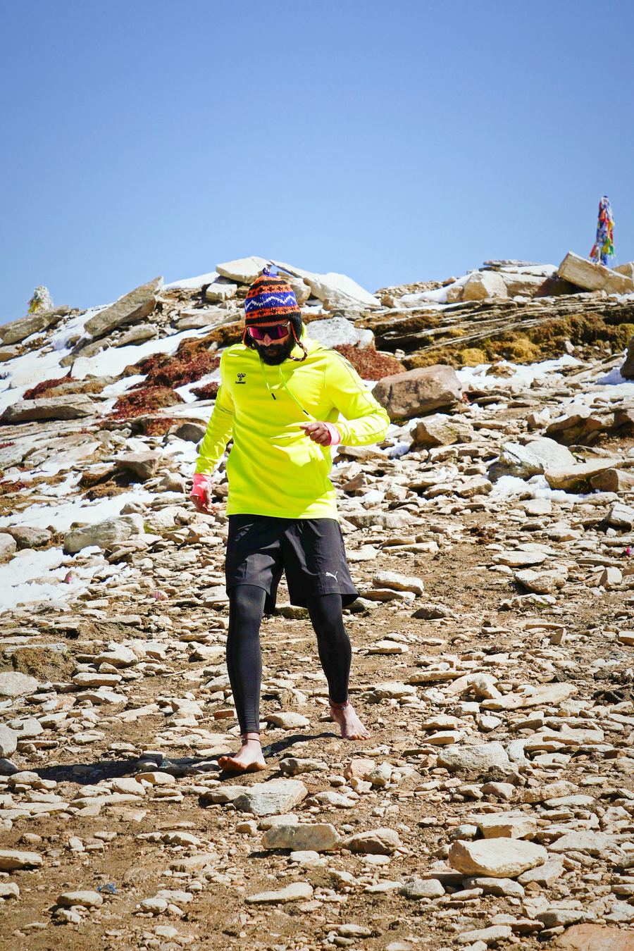 Aakash Nambiar running barefoot across a snow dusted Himalayan ridge